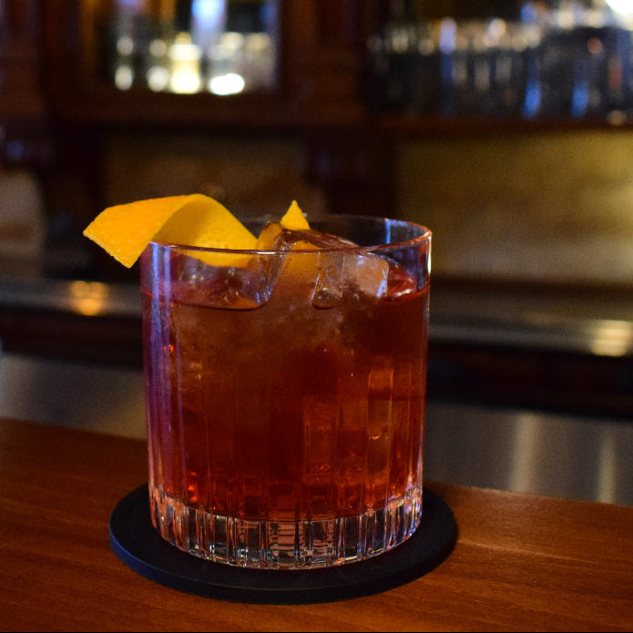 Cocktail with a lemon twist on a bar counter with a blurred bar background