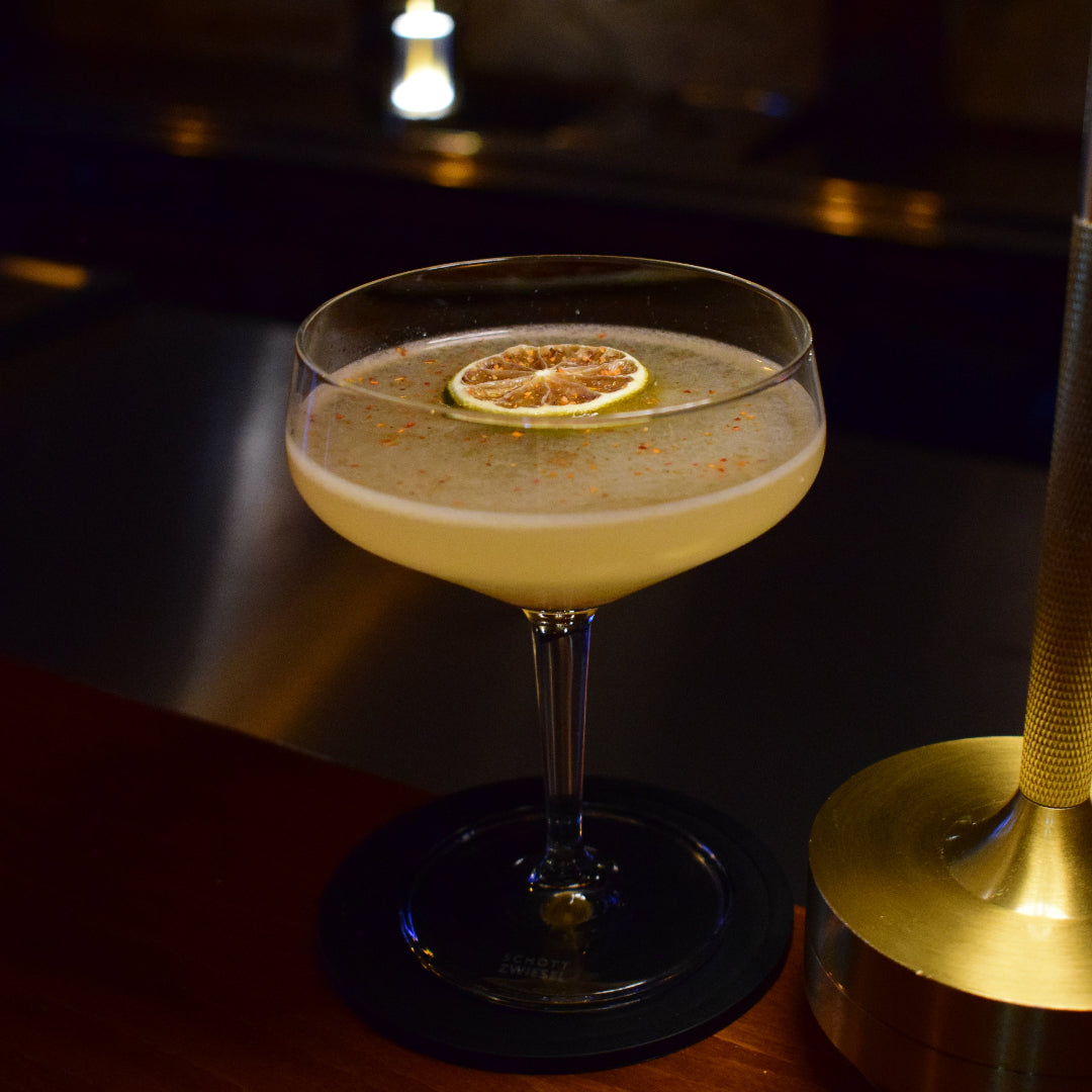 Cocktail in a glass with a gold stirrer on a dark background