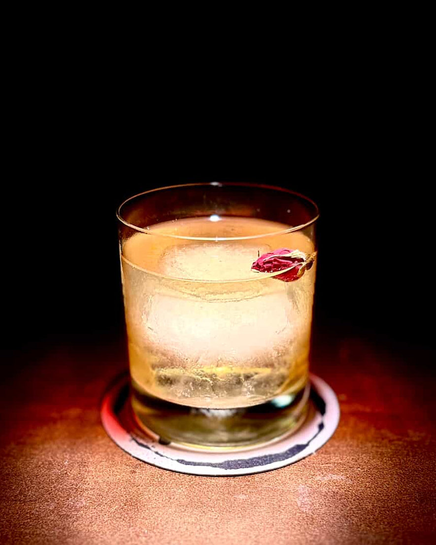Cocktail in a glass with ice and a cherry on a dark background